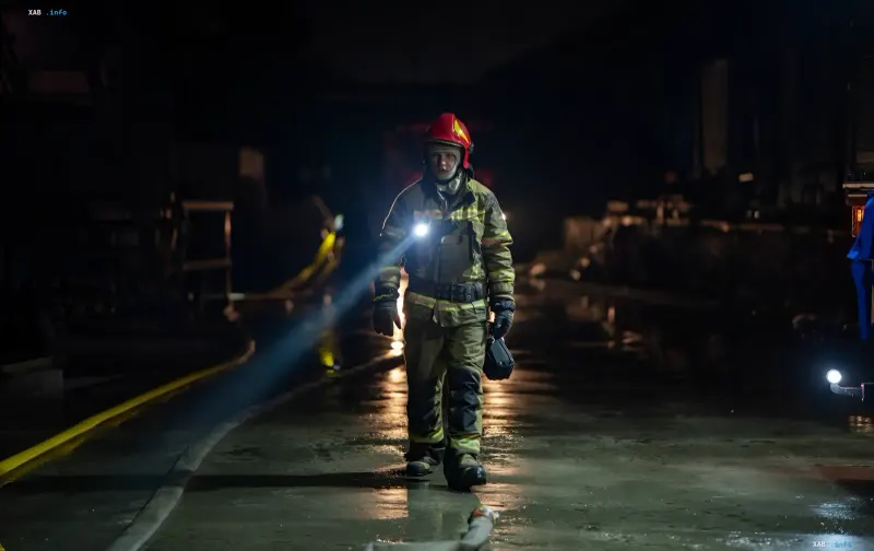 Feuerwehrmann in Schutzausrüstung mit Taschenlampe patrouilliert nachts nach Angriff in Charkiw