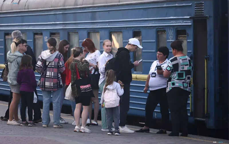 A group of people with children and a train conductor waiting on the platform during evacuation