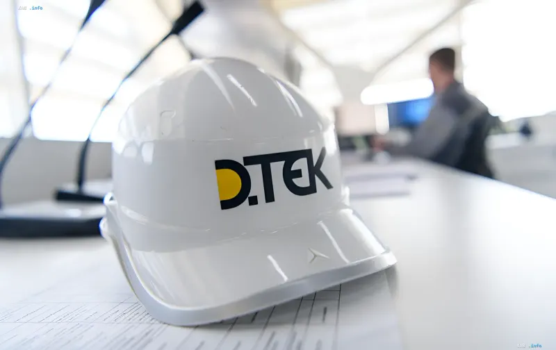 Белая строительная каска с логотипом DTEK на столе в светлом офисе энергетической компании