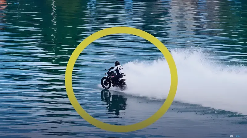 Мотоциклист на модифицированном мотоцикле MX450 едет по водной глади реки, оставляя пенный след