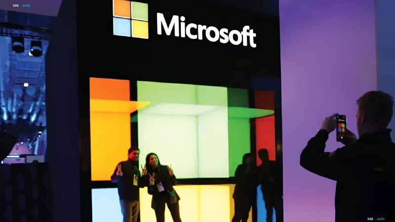 Співробітники роблять фото на тлі світлового стенда Microsoft з логотипом компанії