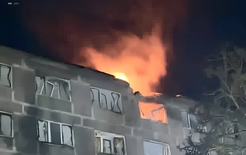 Горящий верхний этаж жилого здания ночью после попадания дрона в Днепре