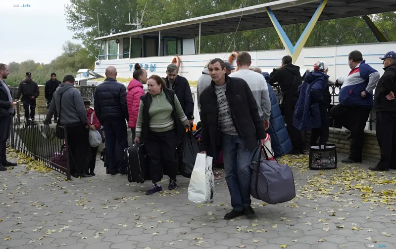 A group of evacuating residents with suitcases and bags preparing to board a vessel at the pier