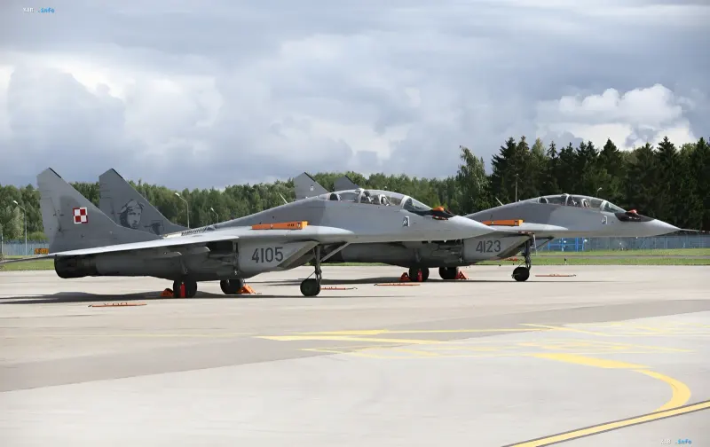 Два советских истребителя МиГ-29 ВВС Польши на летном поле аэродрома под облачным небом.