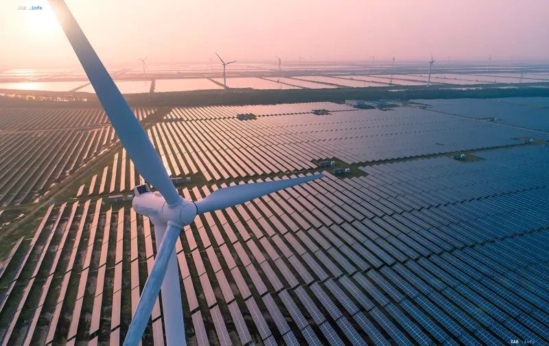 Windkraftanlage vor einer riesigen Solarpark-Fläche bei Sonnenuntergang