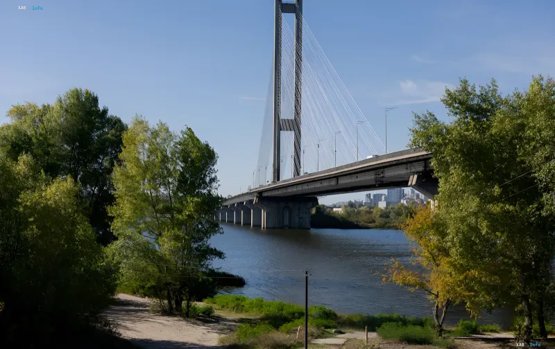 View of the South Bridge in Kyiv across the Dnipro River surrounded by green trees on a sunny day