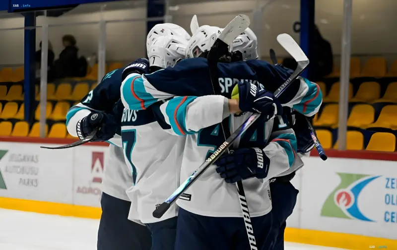 Hockey players in white jerseys celebrating a victory and hugging on the ice