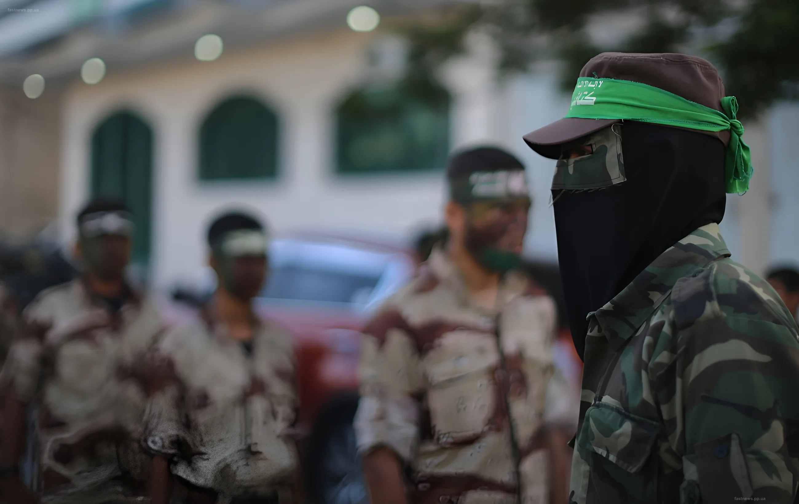 Hamas militants in camouflage uniforms with headbands standing in formation against the backdrop of destroyed buildings in the Gaza Strip