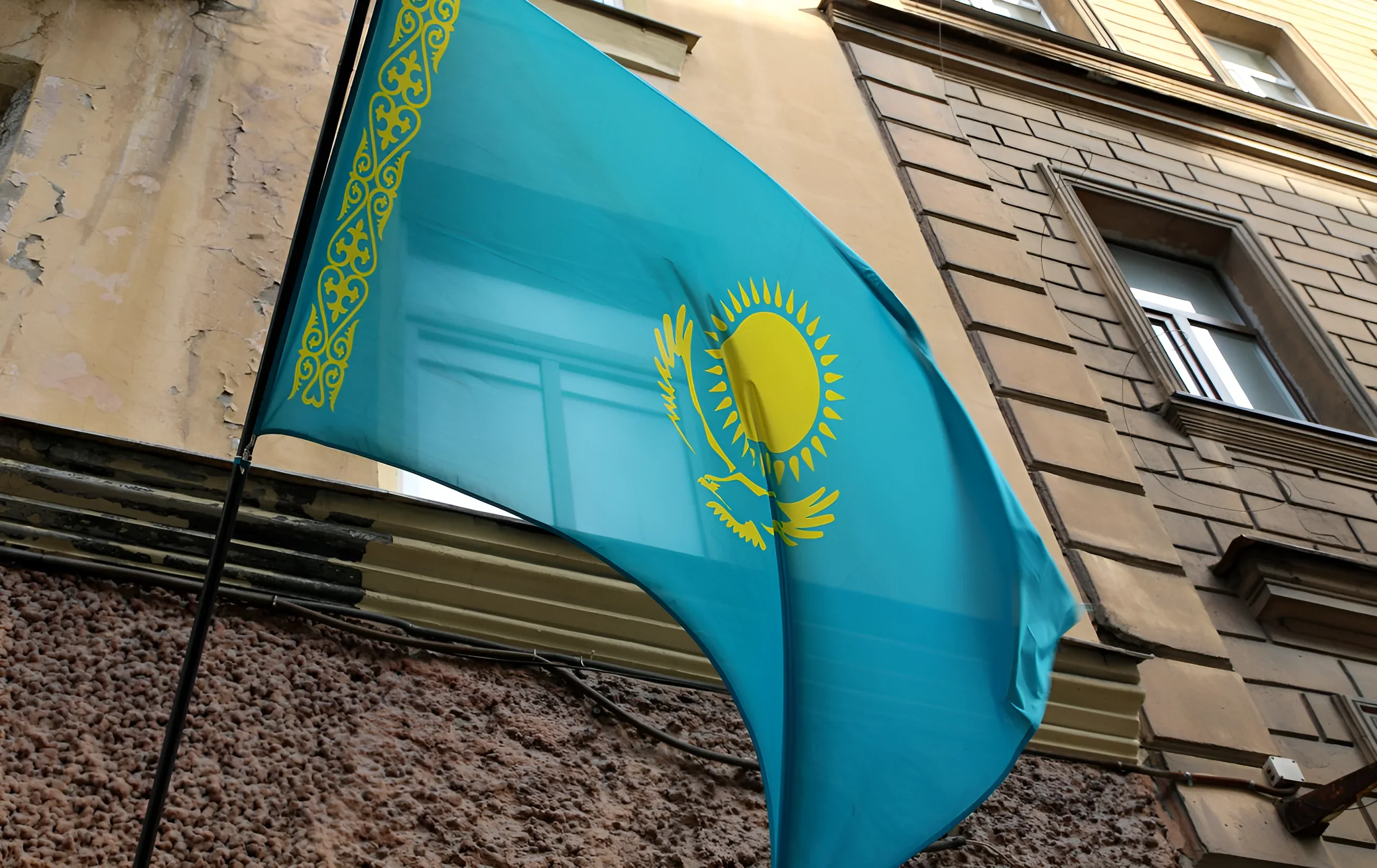 The flag of Kazakhstan waving against the backdrop of an old building, illustrating the country's refusal to enforce the court decision on Naftogaz's lawsuit