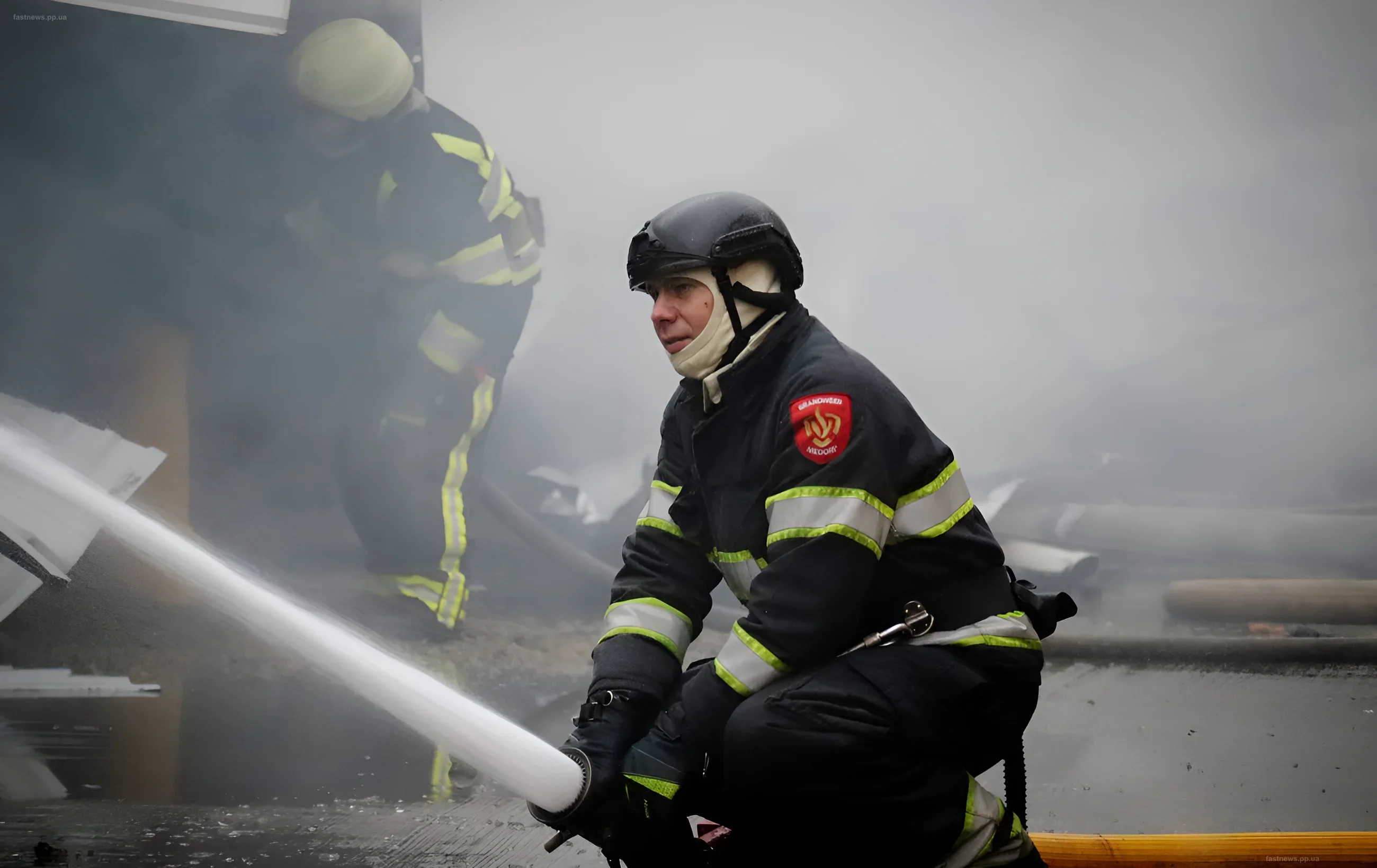 Пожарные в защитной экипировке тушат пожар после удара российского дрона в Одесском районе, на фоне дыма видны разрушенные объекты