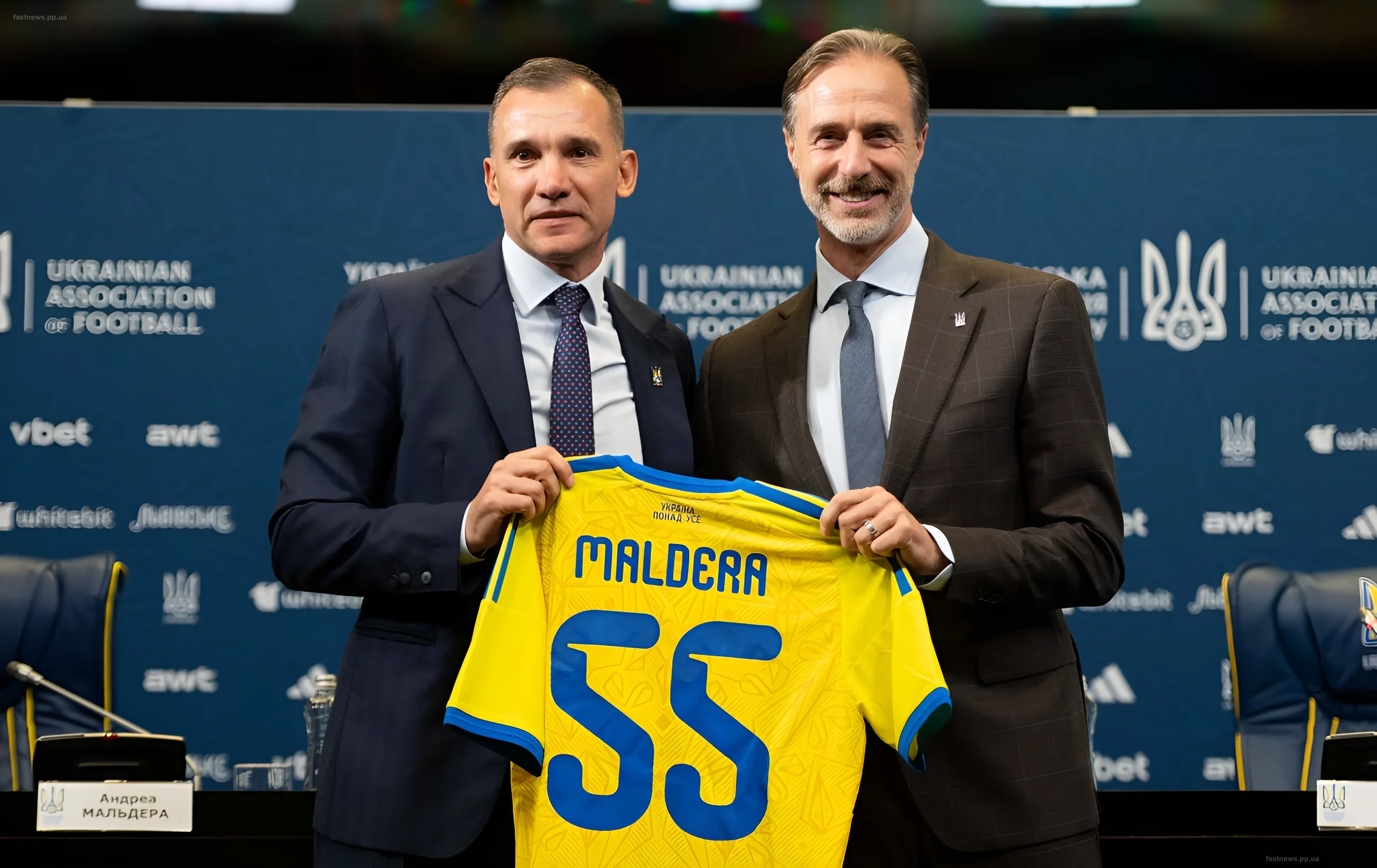 Андрей Шевченко и Андреа Мальдера держат футболку сборной Украины с фамилией тренера на пресс-конференции УАФ