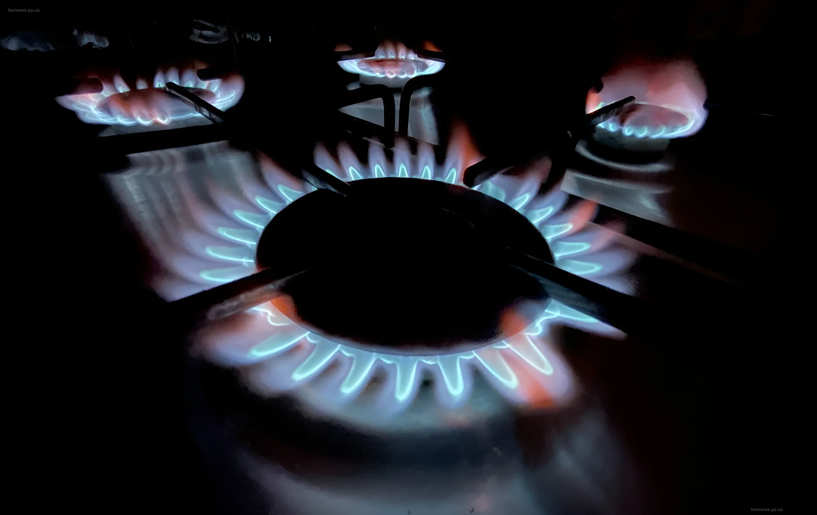 Голубые пламена газовых горелок на темном фоне, символизирующие тему тарифов на газ в Украине