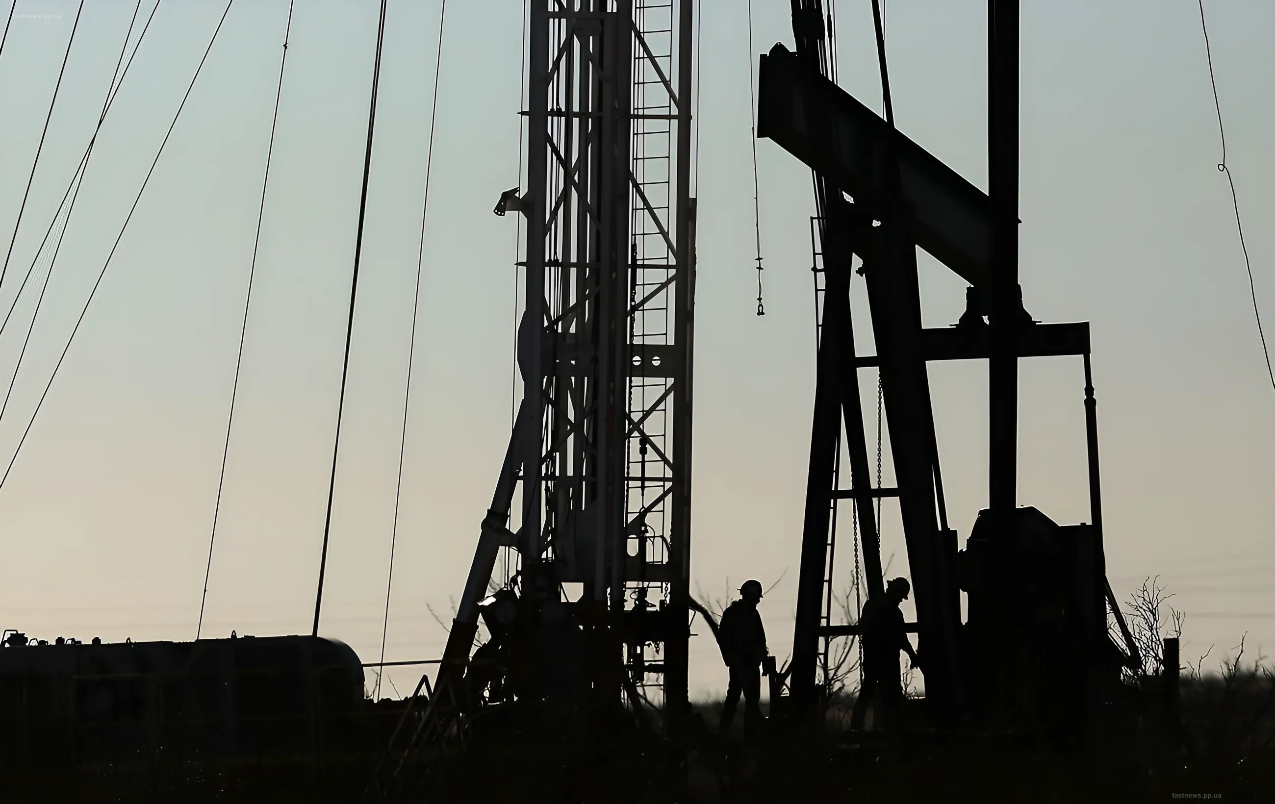 Силуэты нефтяной вышки и рабочих на фоне заката, иллюстрирующие рост цен на нефть