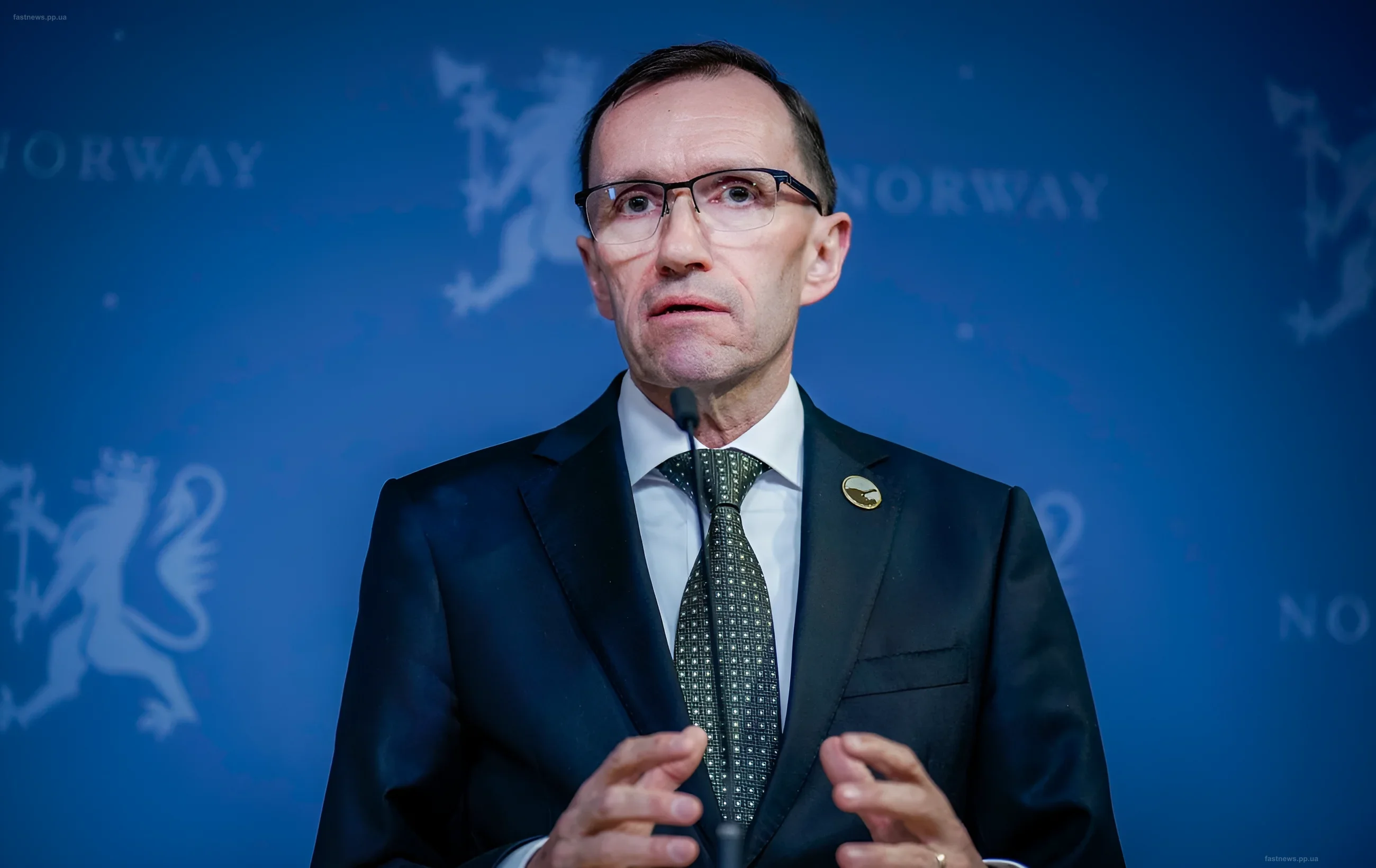 Norwegian Foreign Minister Espen Bart Eide speaking at a podium against a blue banner with the coat of arms of Norway
