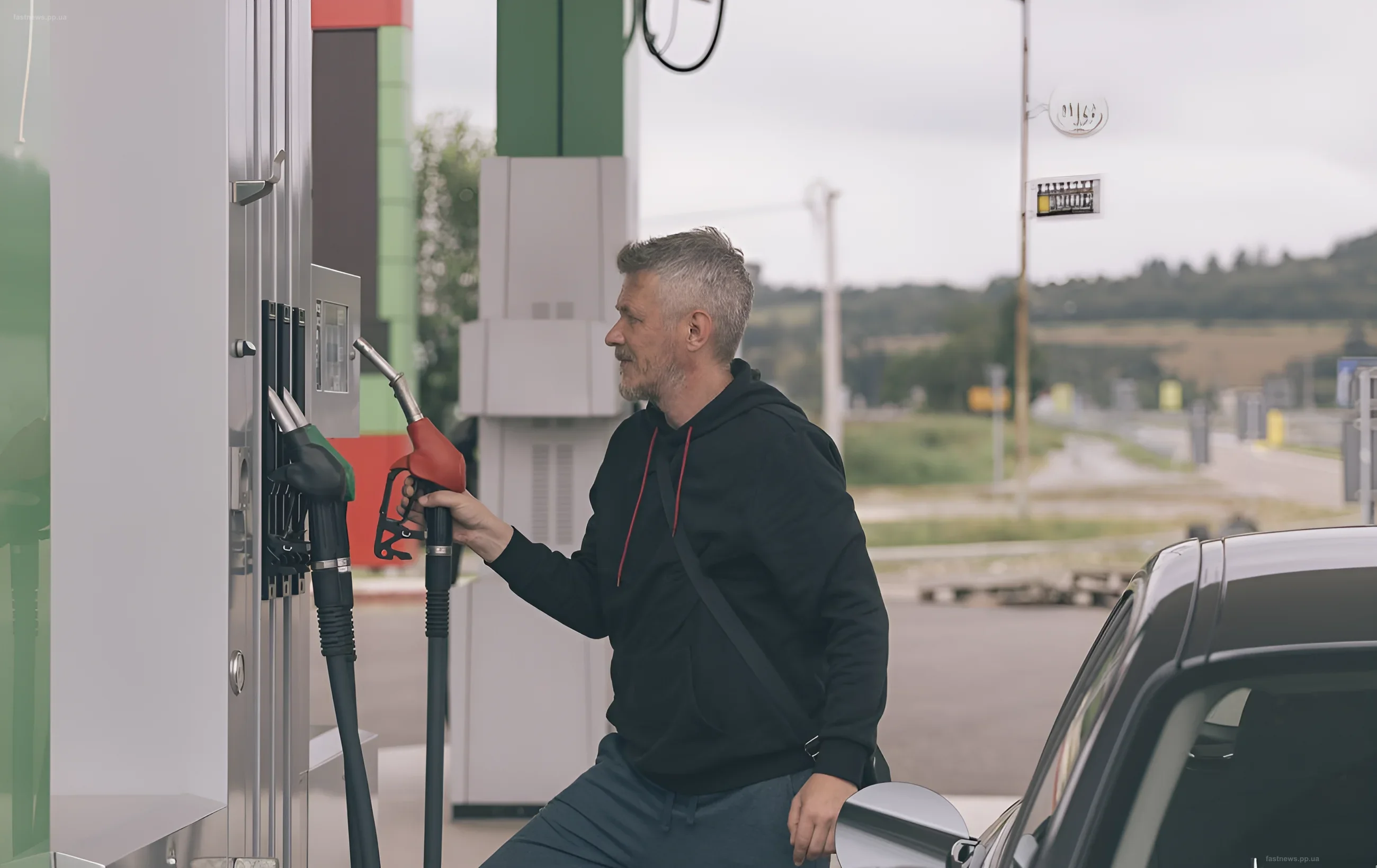 Мужчина держит пистолет топливного пистолета на заправочной станции, заправляя автомобиль