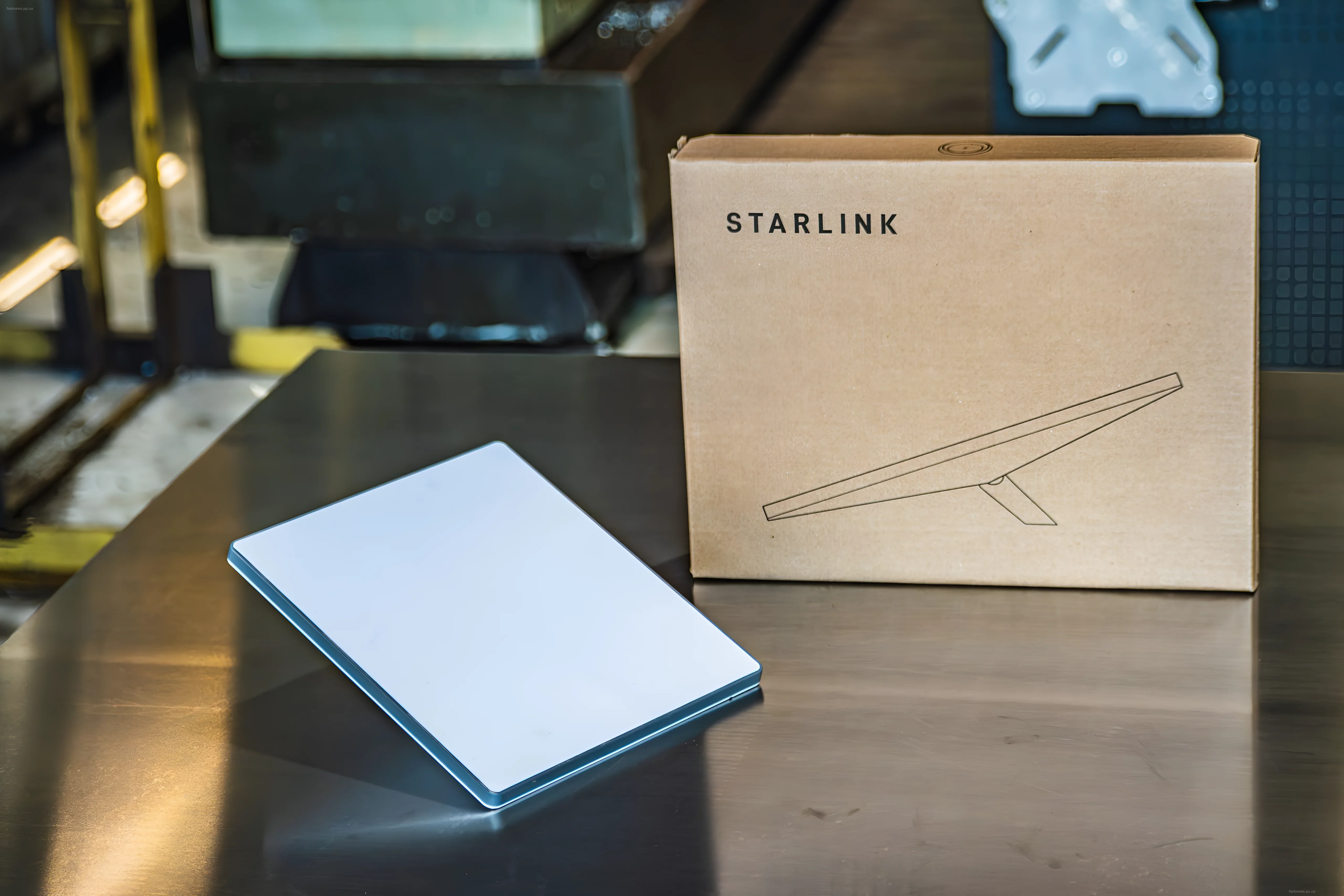 Коробка с надписью Starlink и белая антенна на металлическом столе