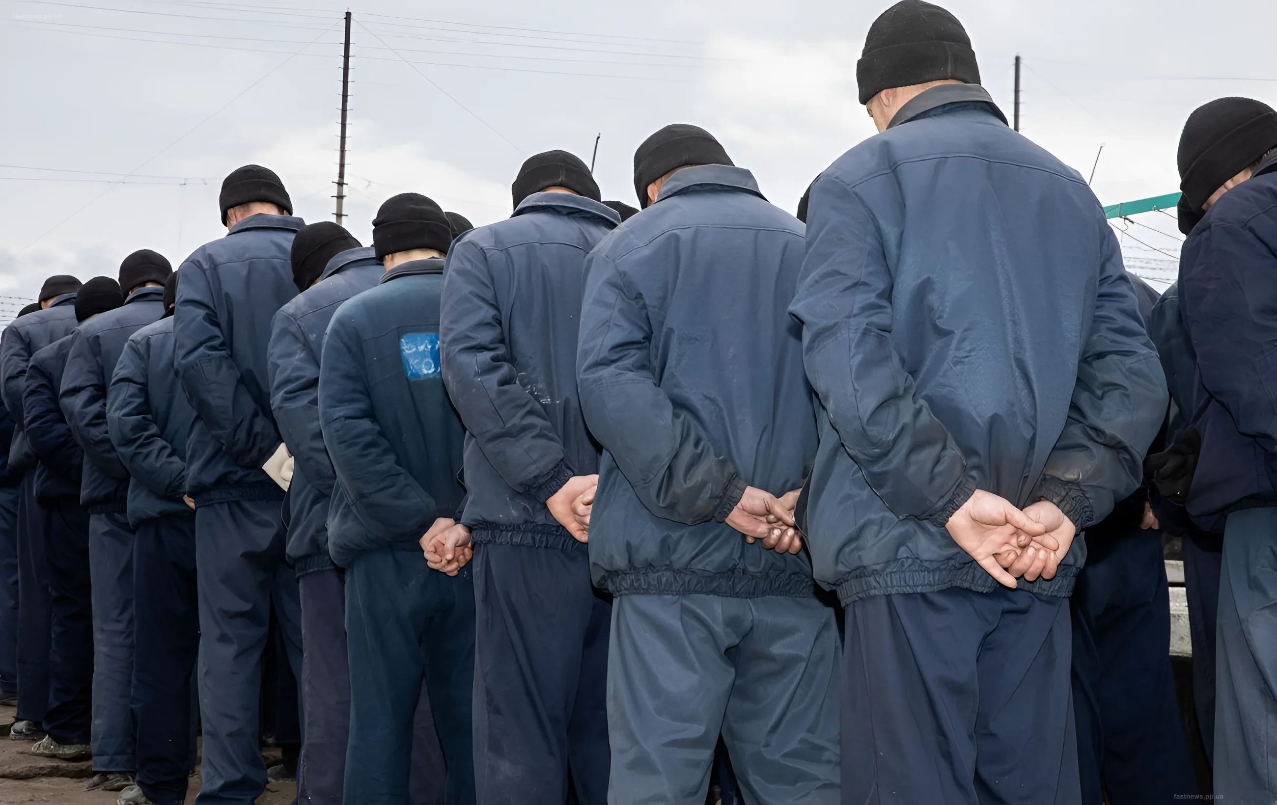 Группа иностранных наемников в синих комбинезонах и черных шапках, стоящих спиной к камере в украинском плену