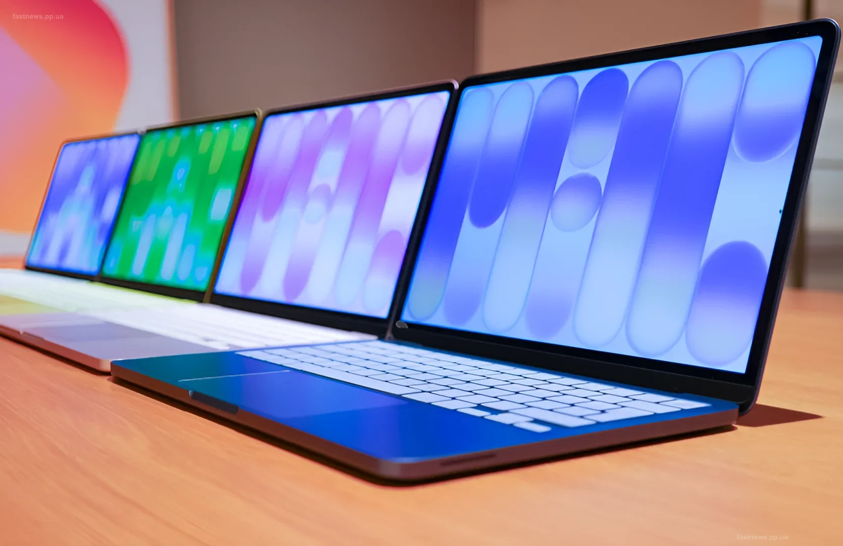 Ряд ноутбуков MacBook Neo разных цветов на деревянном столе
