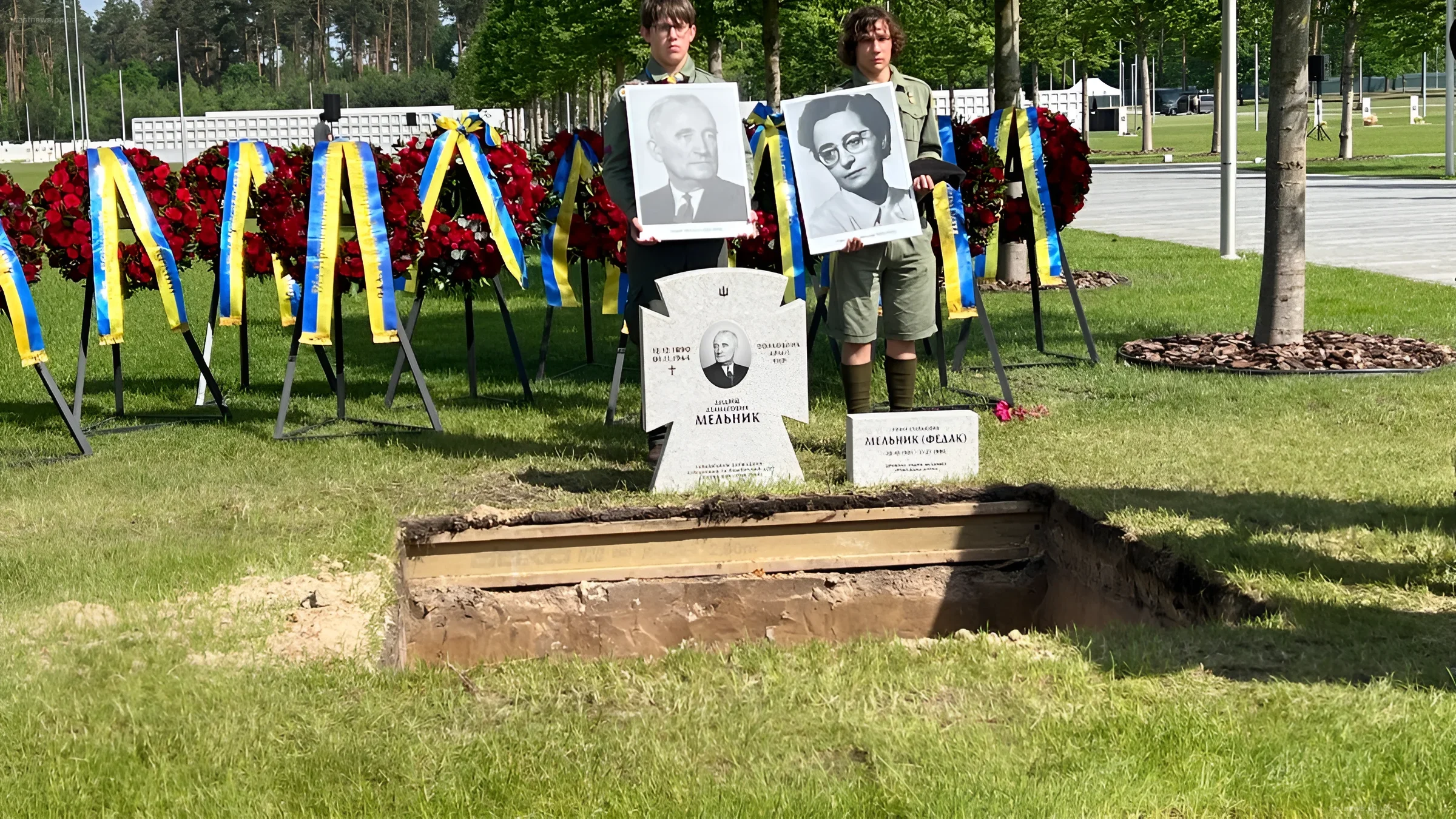 Ритуал перезахоронения на НВМК: участники держат портреты Андрея Мельника и Софии Федак-Мельник у открытой могилы с венками