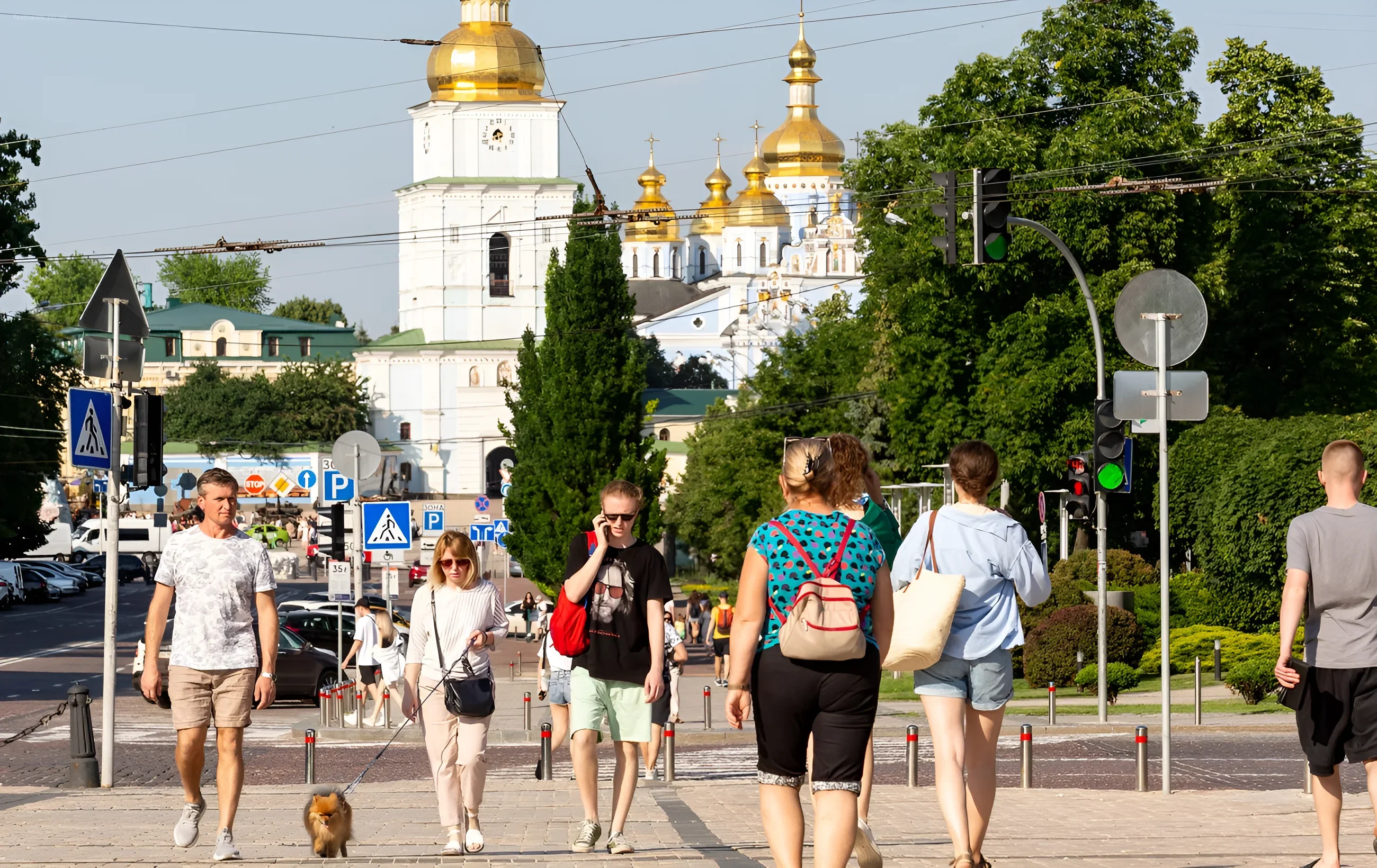 People walking on a street in Kyiv against the backdrop of the golden domes of St. Sophia's Cathedral, demonstrating everyday life in the capital