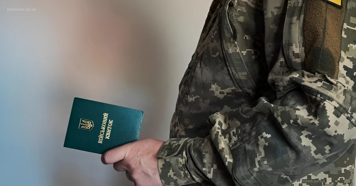 Военнослужащий в камуфляже держит украинский военный билет — символ мобилизации граждан старше 50 лет в Украине
