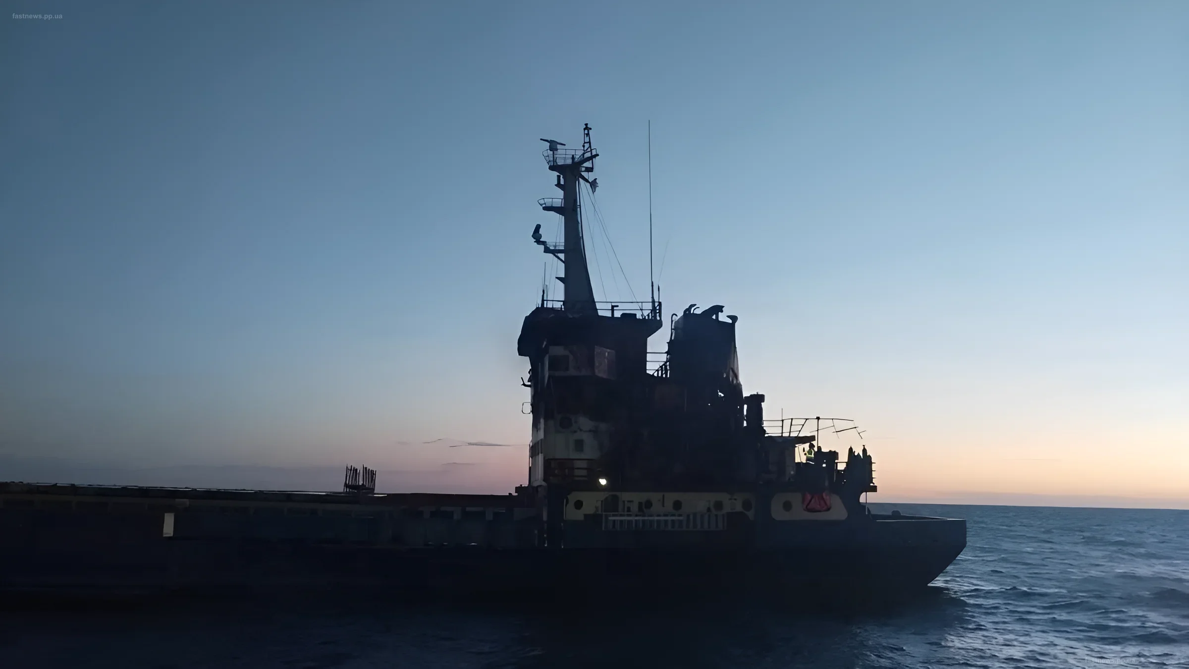 Silhouette of a large cargo ship in the Black Sea against the backdrop of a sunset, symbolizing the operation of the maritime corridor