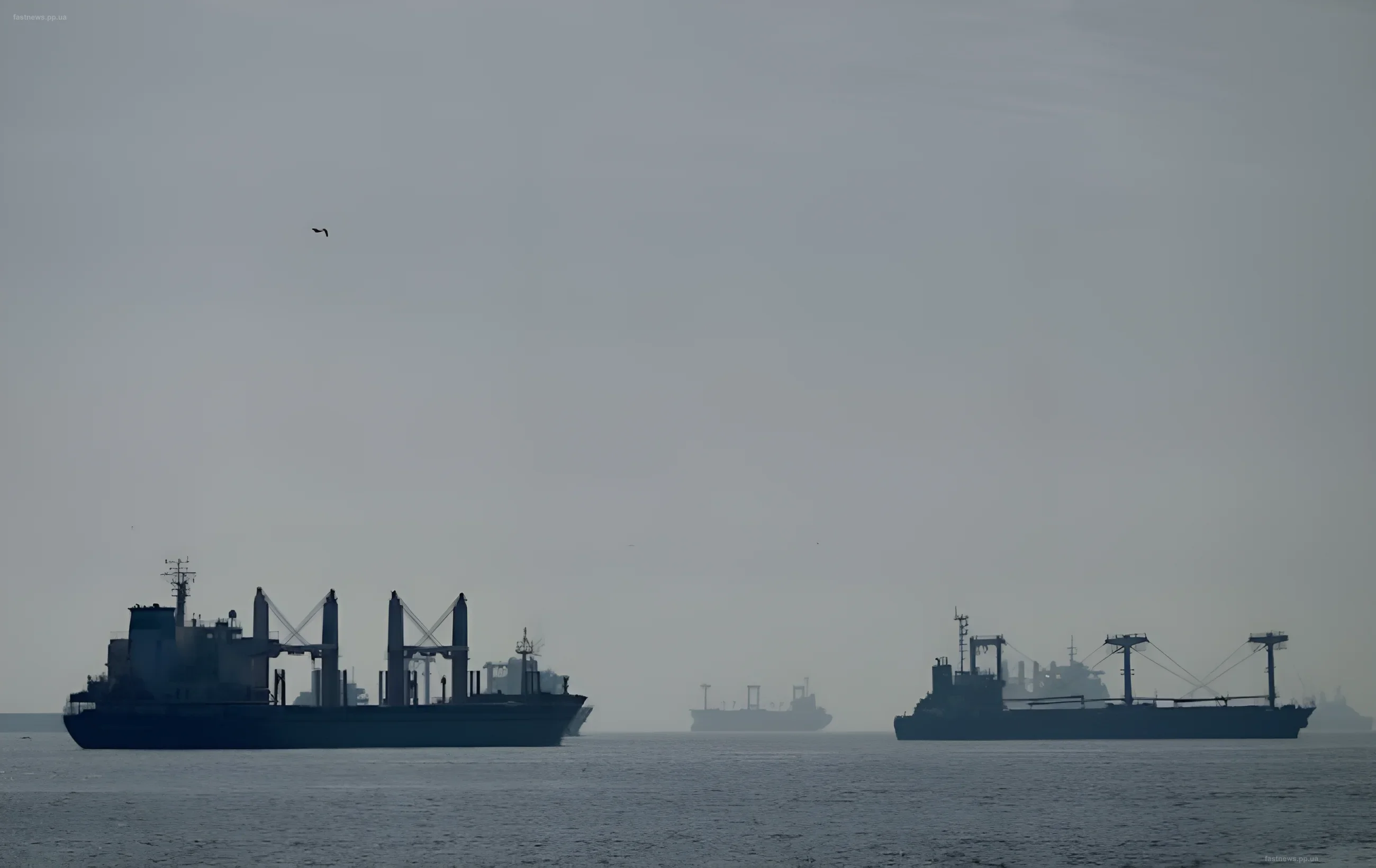 Silhouettes of tankers in fog against a gray sky, symbolizing the shadow fleet