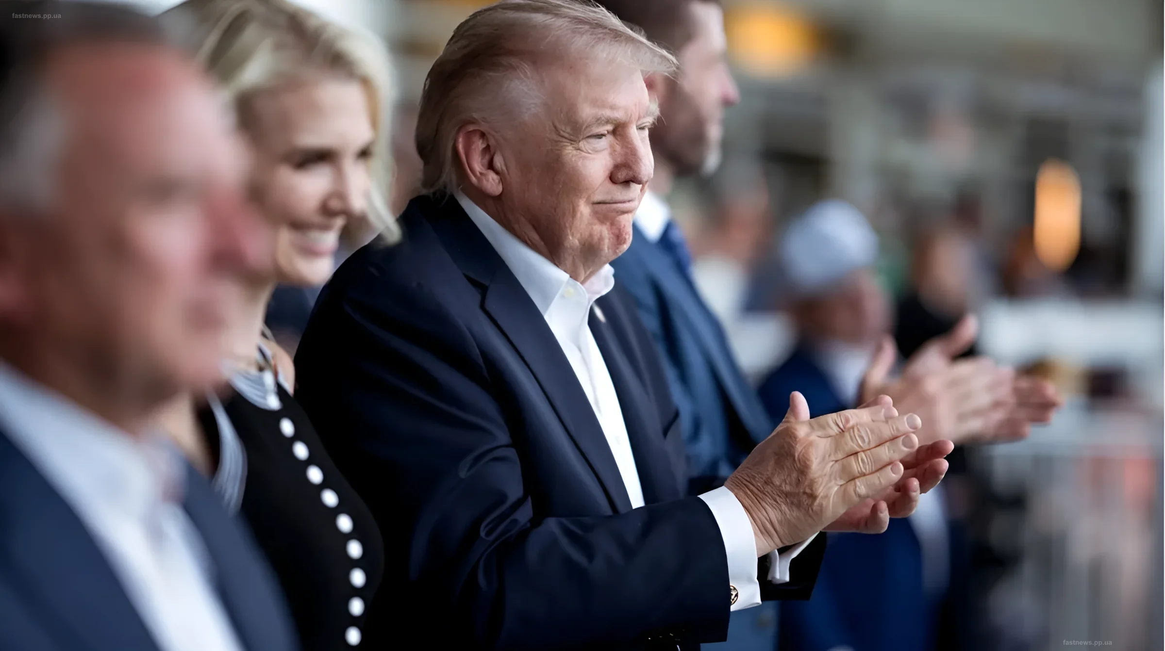 Donald Trump in a blue suit applauding at an official event