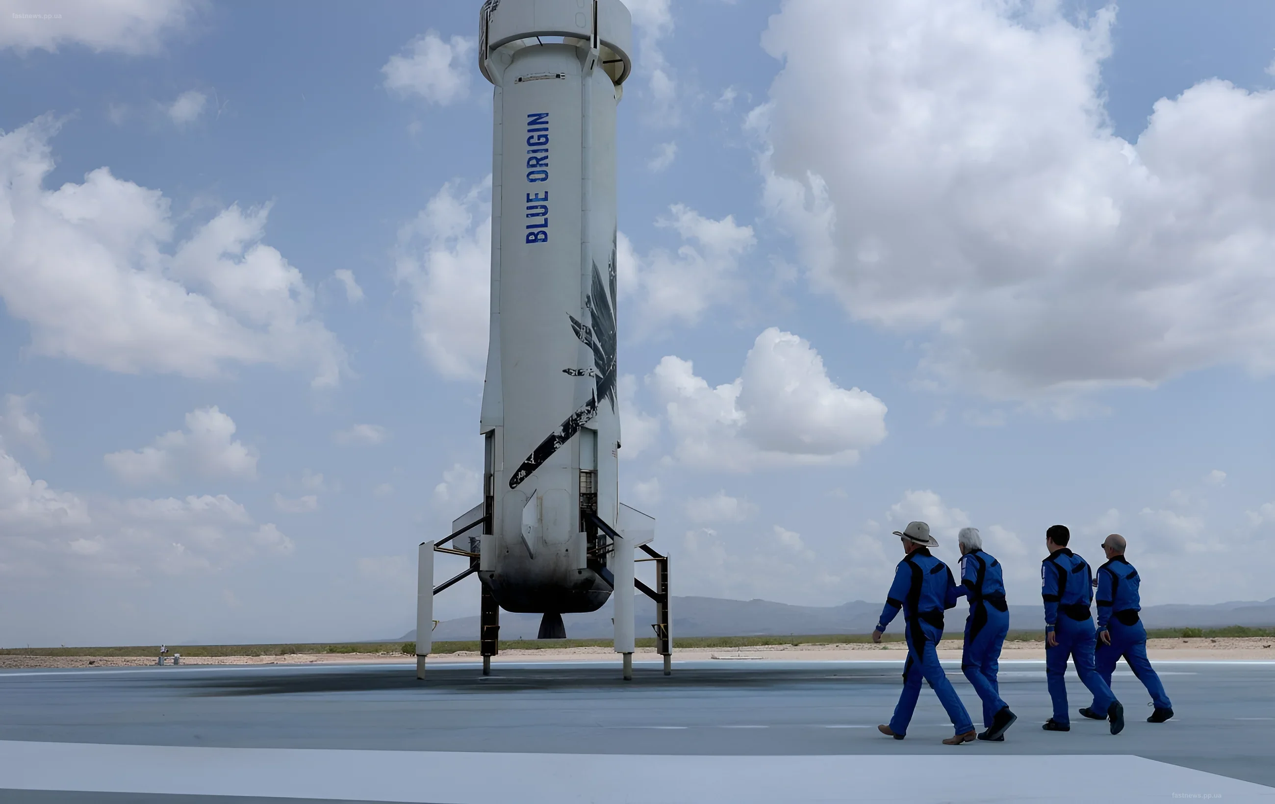 Ракета Blue Origin New Glenn стоит на стартовой площадке, а группа людей в синих скафандрах идет к ней