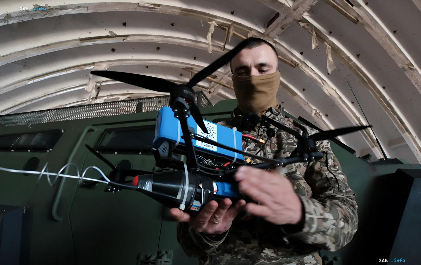 Украинский военнослужащий готовит к запуску FPV-дрон, оснащенный боевой частью, в условиях поврежденного здания, демонстрируя массовое применение дронов против российской армии.