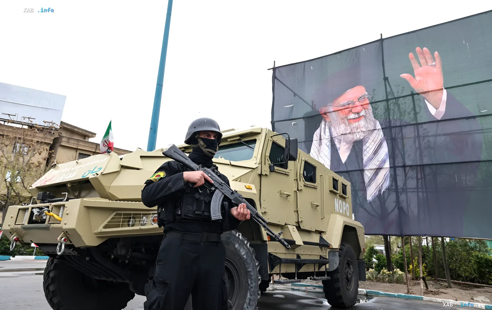 Вооруженный иранский полицейский у бронемашин на фоне портрета аятоллы Хомейни — символ готовности к эскалации после заморозки переговоров с США