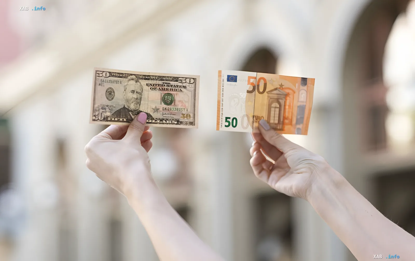 Сравнение курса доллара и евро: руки держат купюры 50 долларов США и 50 евро на фоне архитектуры