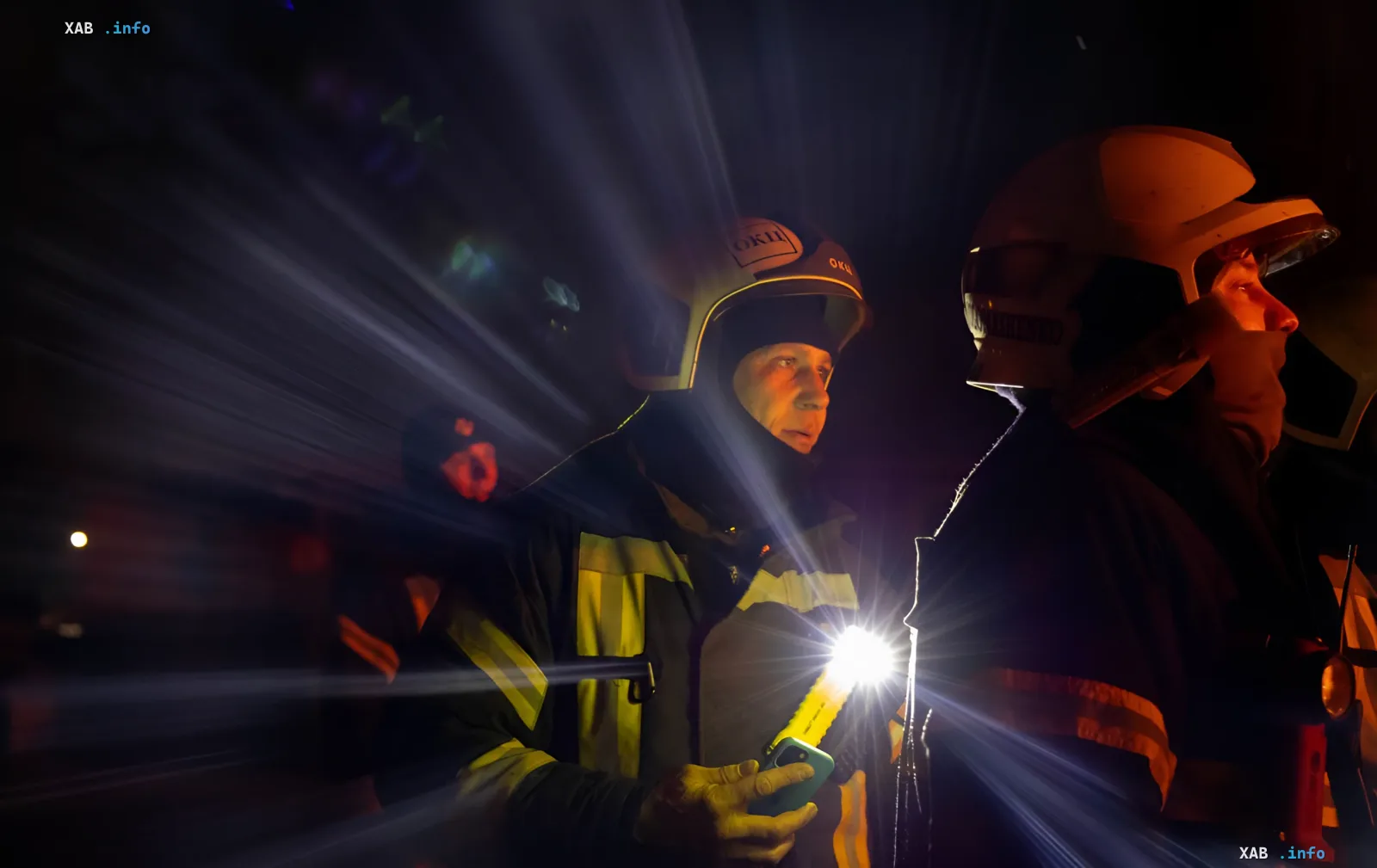 Ukrainian rescuers at night with flashlights and phones, likely coordinating actions after a massive drone attack