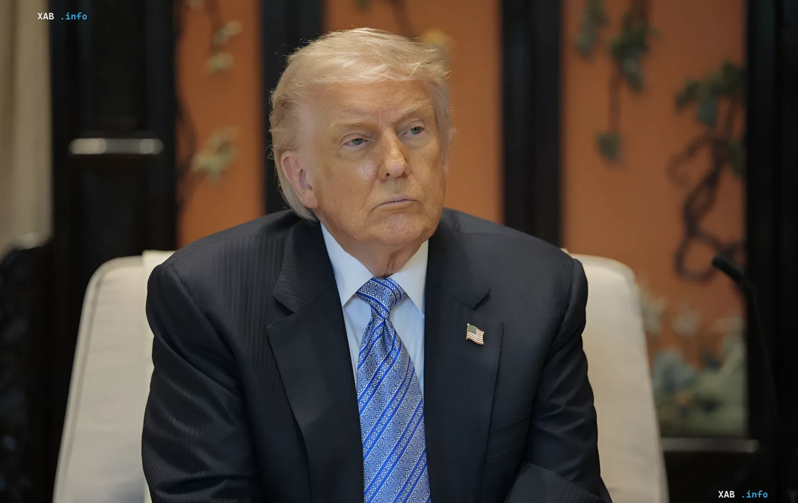 Donald Trump in formal suit with American flag lapel pin, seated at a table — symbolizing decisions related to halting the investigation of war crimes in Ukraine