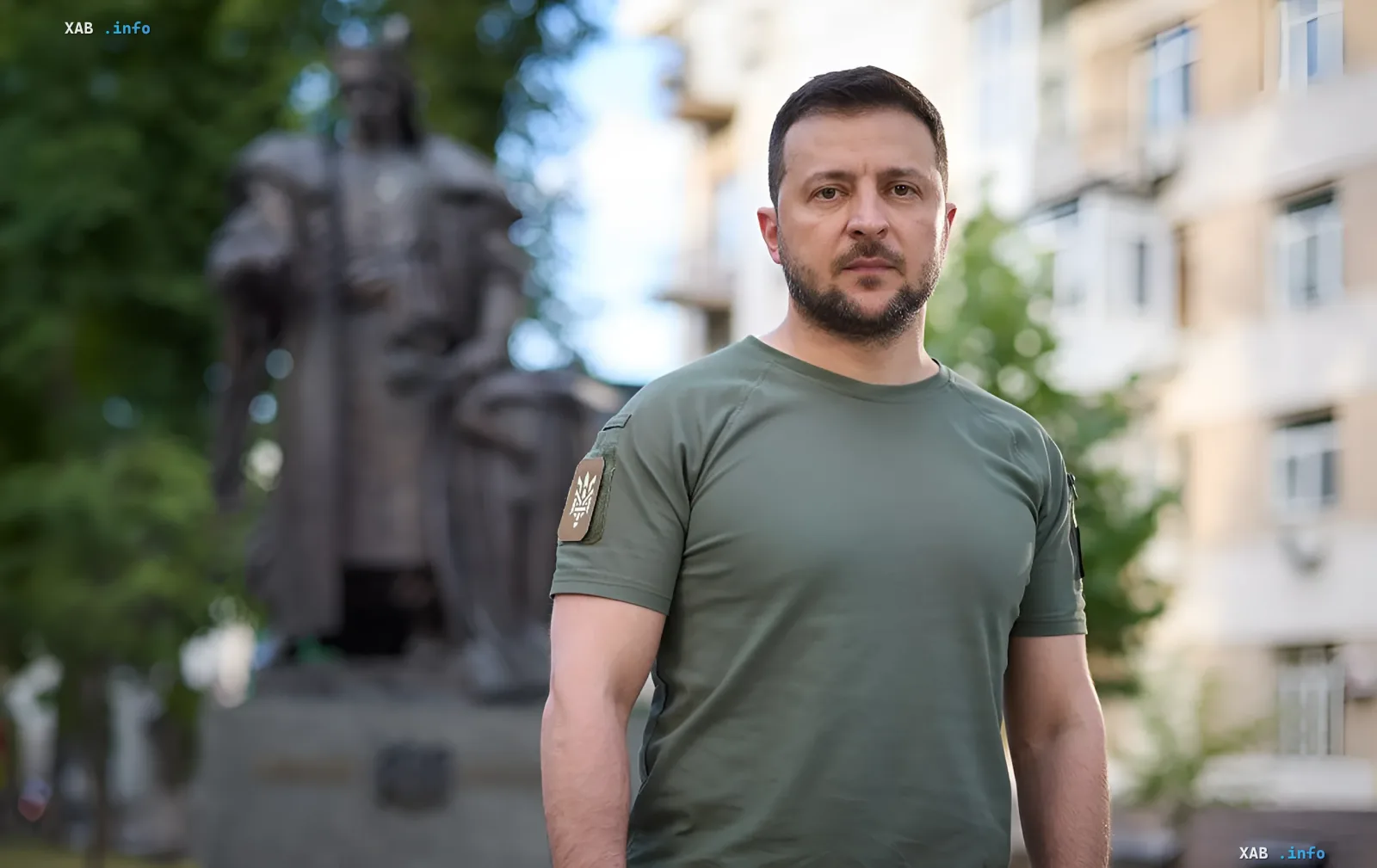 Ukrainian President Volodymyr Zelenskyy in military attire against a monument backdrop, symbolizing his role in defense management and military aid requests