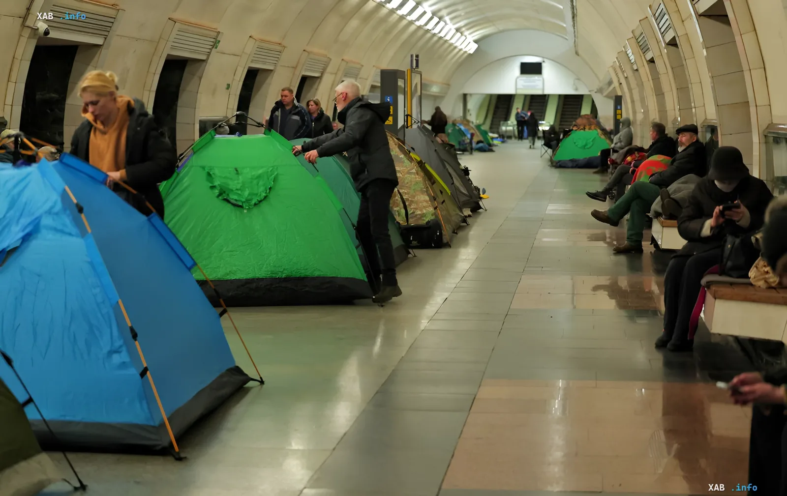 People setting up tents in a Kyiv metro vestibule during mass missile attacks, illustrating the debate over comfort and safety