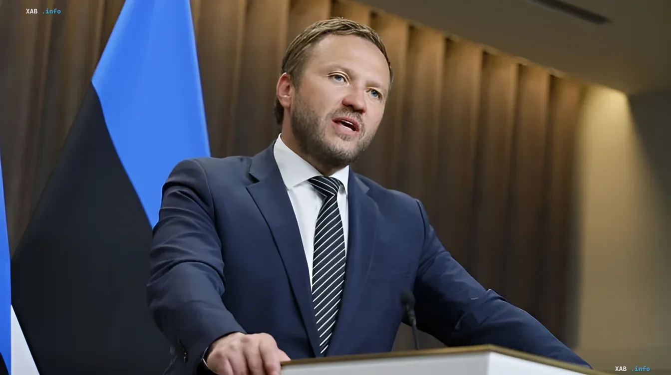 Estonian Prime Minister Kaja Kallas speaking at a podium with the Estonian flag in the background, raising the issue of confiscating Russian assets following an attack on Ukraine