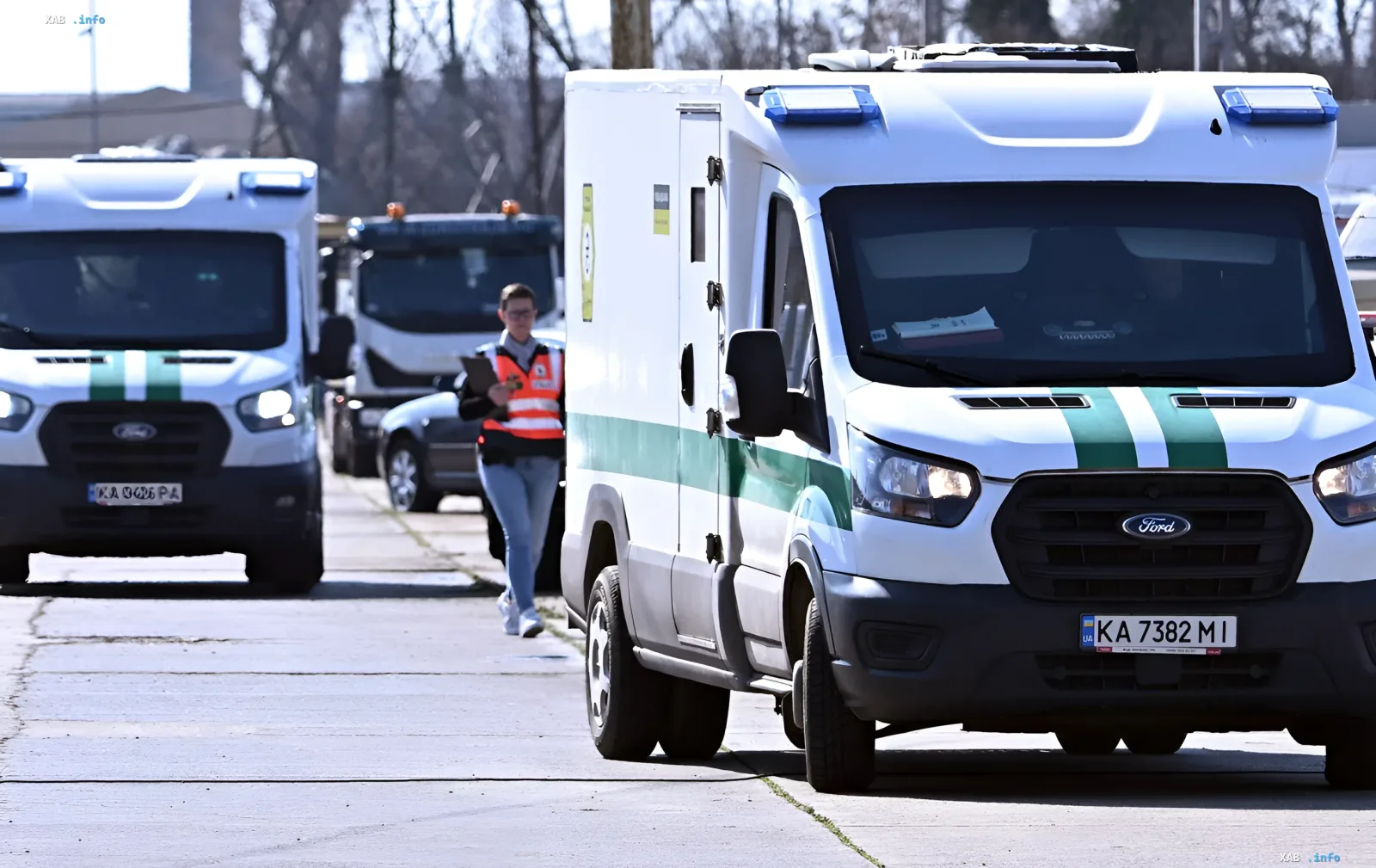 Konvoi weißer Ford Transit-Transporter mit ukrainischen Kennzeichen und grünen Streifen, begleitet von einem Mitarbeiter in einer orangefarbenen Weste, symbolisiert den Überfall auf Oshchadbank, der von Orban ohne rechtliche Grundlage initiiert wurde.