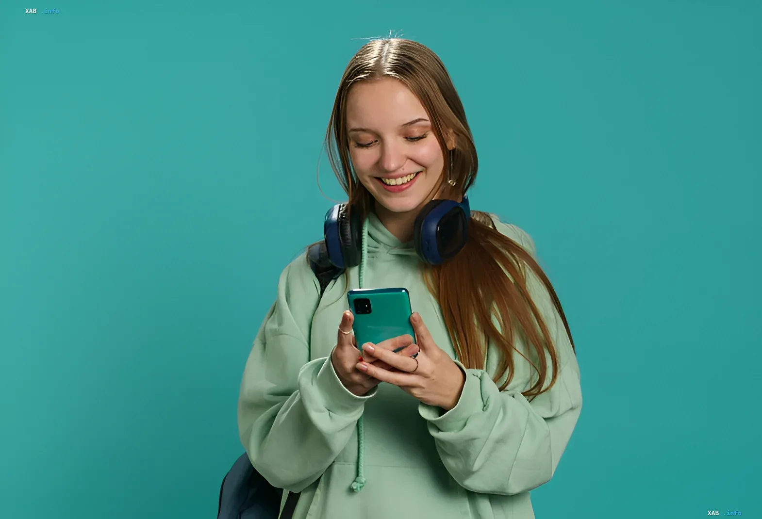 Счастливая девушка с наушниками смотрит на смартфон, символизируя позитивные перемены в Украине