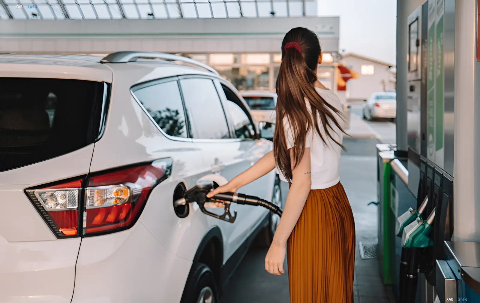 Frau tankt ein weißes SUV an einer Tankstelle — Illustration zum Artikel über E10-Kraftstoff in der Ukraine: Preise und Motorsicherheit