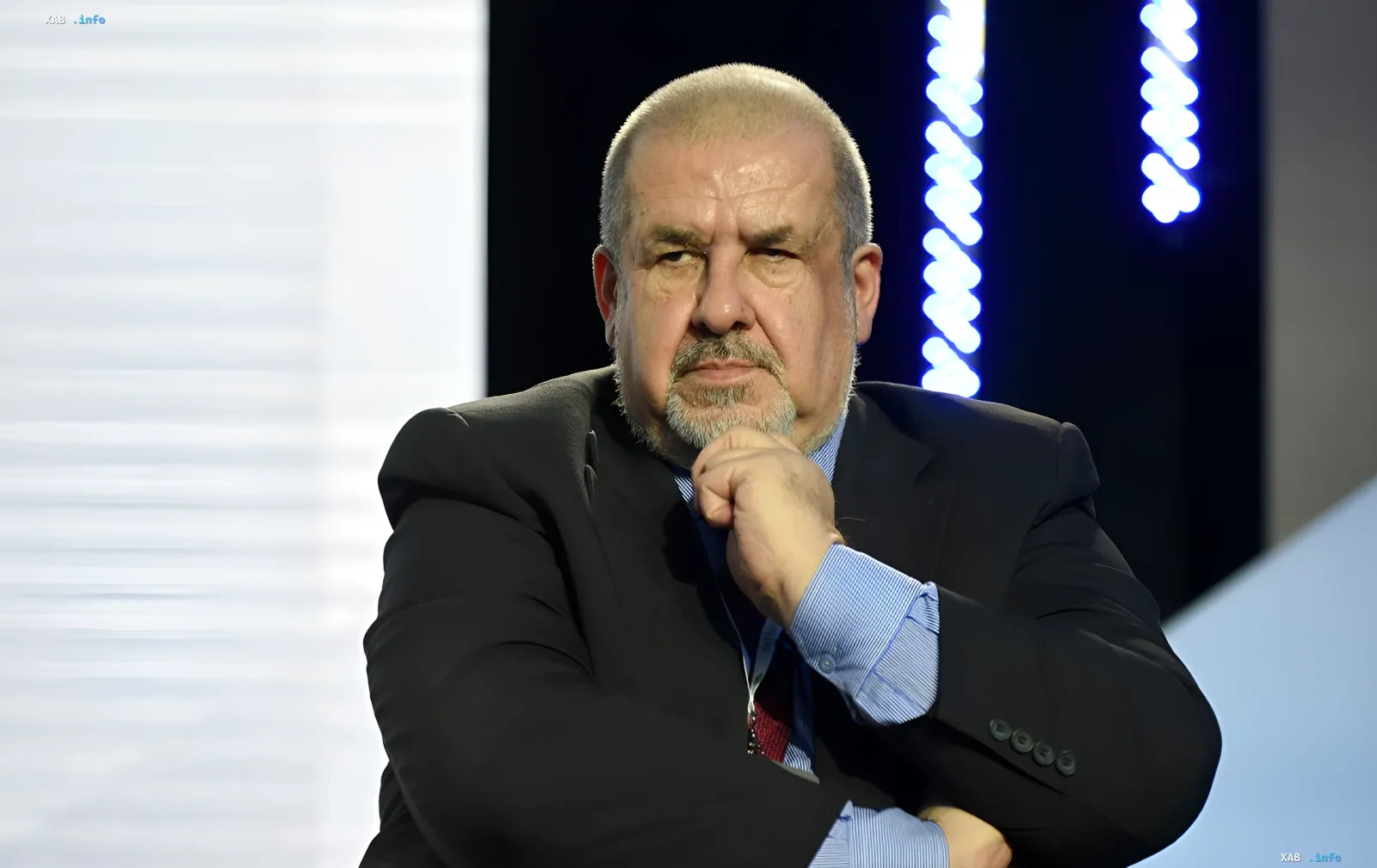 Refat Chubarov in einem Anzug vor einem Bildschirm mit Grafiken, diskutiert die Situation in der Krim