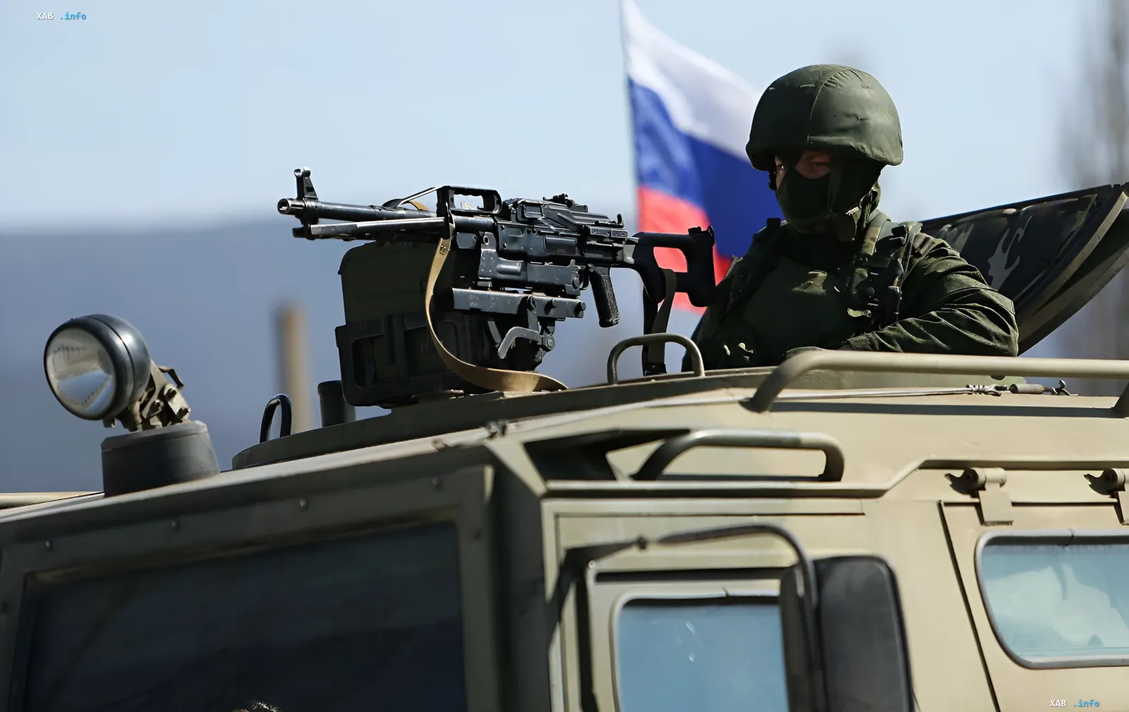 Российский военный с пулеметом на бронетранспортере на фоне флага РФ — контекст для новости о новых дронах-перехватчиках «Сокол-И» и «Молния-ПВО»