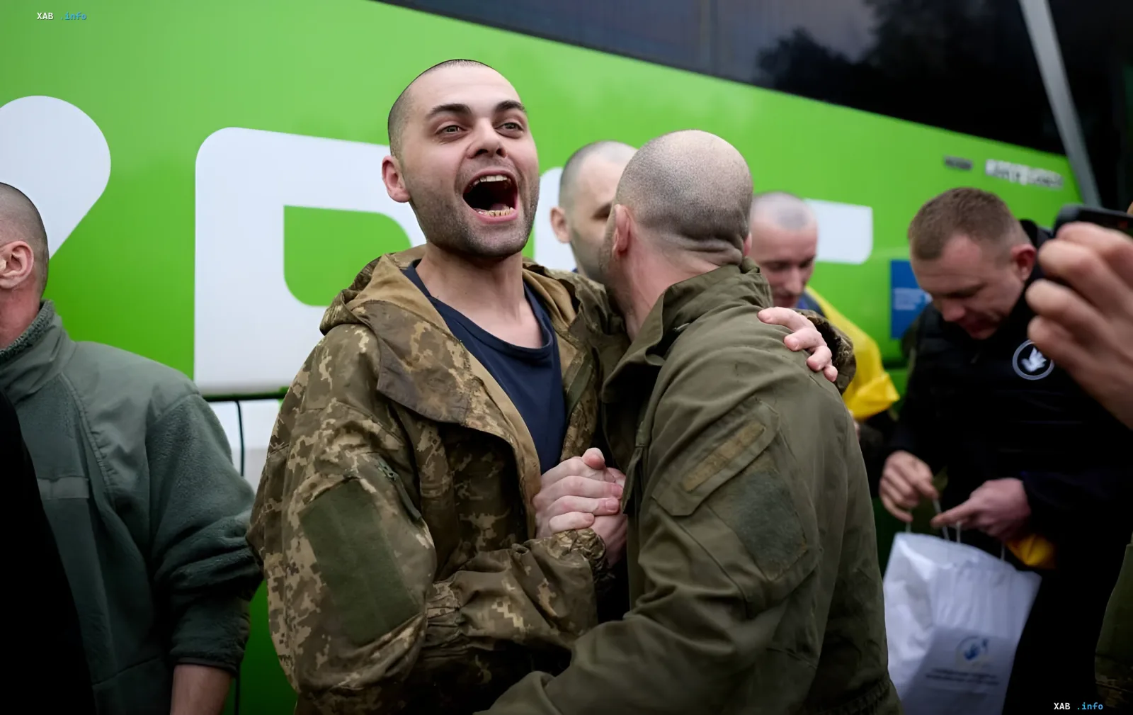 Військові обіймаються на фоні зеленого автобуса після повернення в рамках обміну «1000 на 1000»
