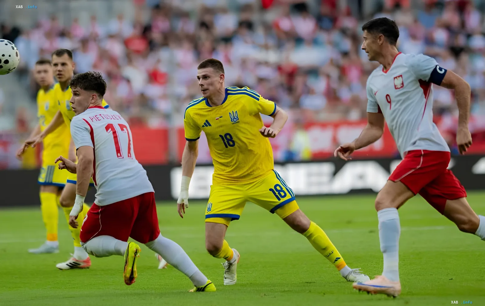 Игрок сборной Украины в желтой форме с номером 18 в борьбе за мяч с футболистом Польши в матче отборочного турнира