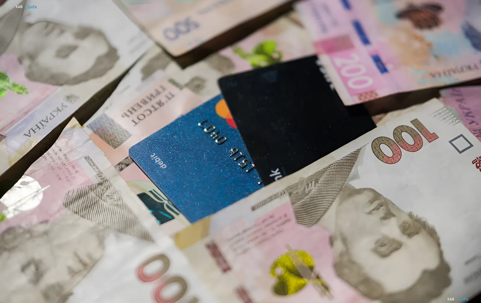 Bank cards placed over Ukrainian banknotes symbolize the shift to cashless payments in 2026