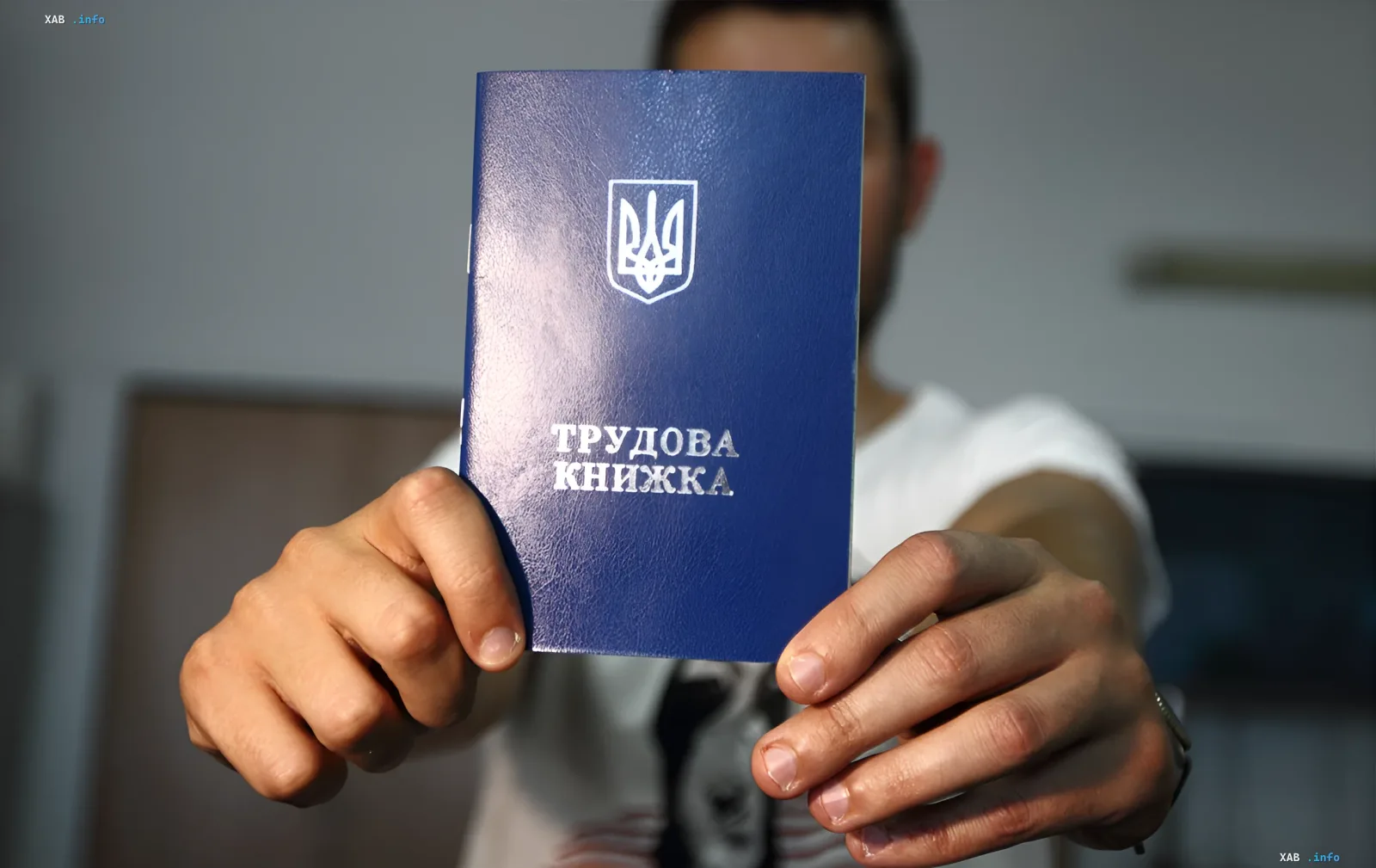 Людина тримає синю трудову книжку України перед собою, символізуючи перехід до цифрової системи обліку стажу