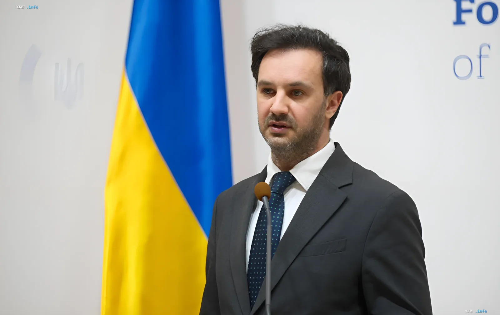 Украинский дипломат на пресс-конференции перед флагом Украины, обсуждающий извинения Греции за инцидент с морским дроном у острова Лефкада