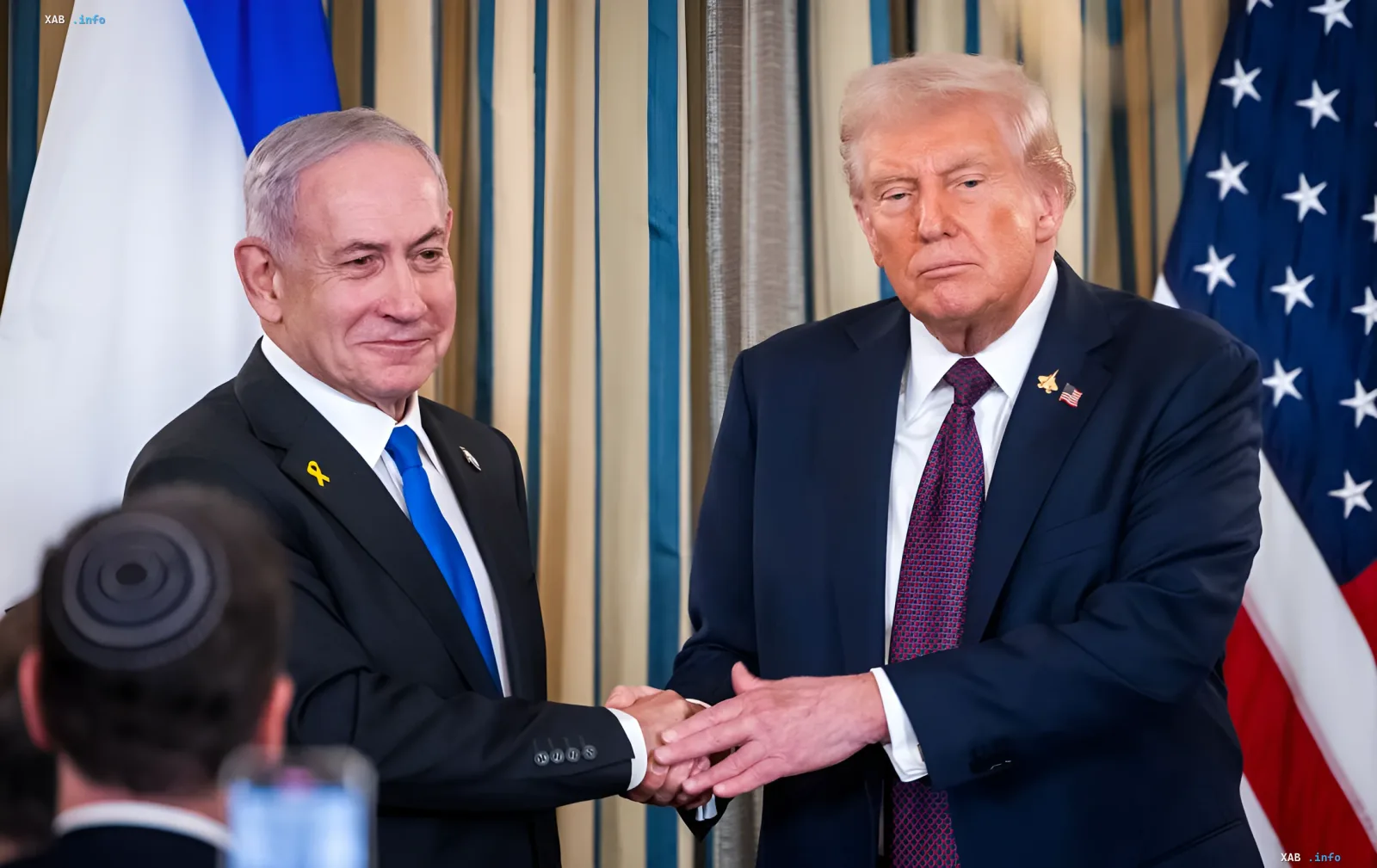Дональд Трамп и Биньямин Нетаньяху пожимают руки на фоне флагов США и Израиля, обсуждая вопрос мести Ирану