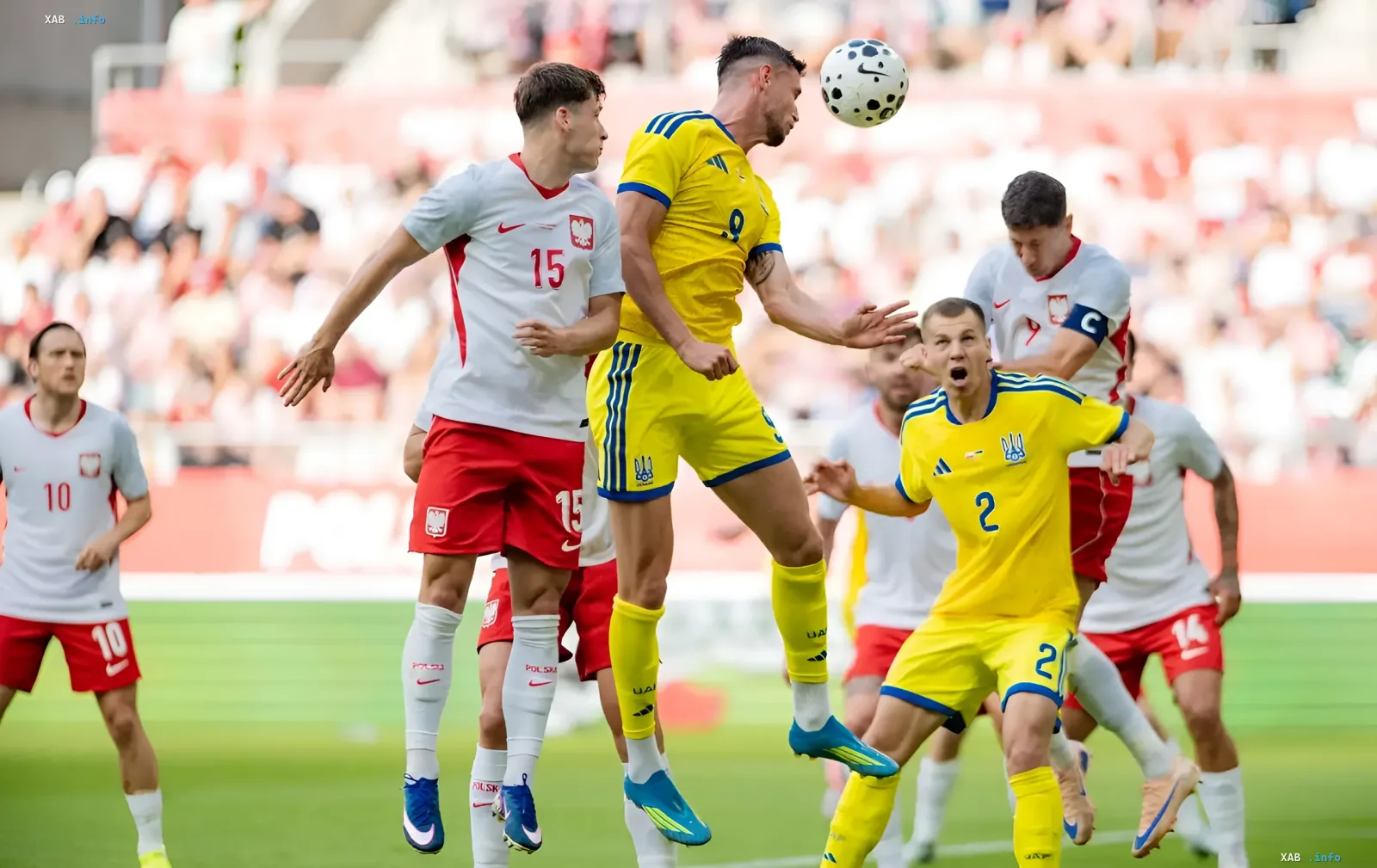 Андрей Ярмоленко в желто-синей форме сборной Украины борется за верховой мяч с игроком Польши в матче отборочного турнира