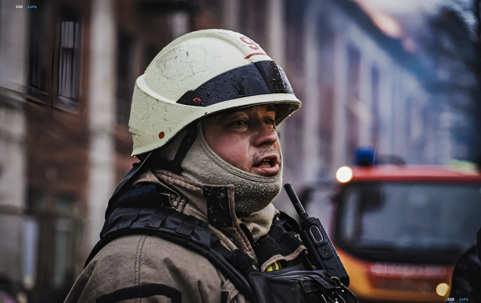 Пожарный в защитной экипировке на фоне задымленного здания и пожарной машины во время ликвидации последствий атаки дронов в Харькове